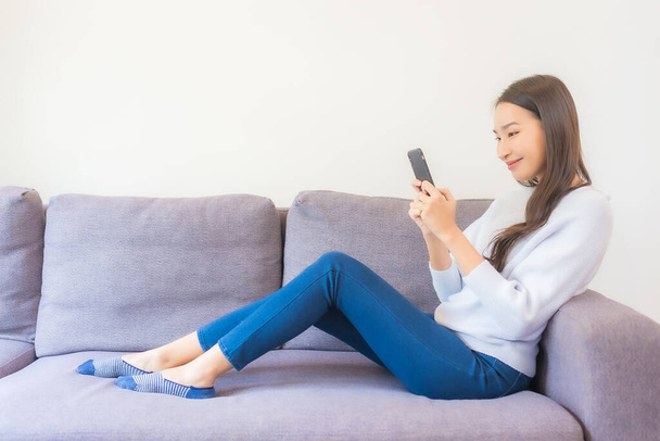 Porträt schöne junge Asiatin nutzt Smartphone auf Sofa im Wohnzimmer - Foto, Bild