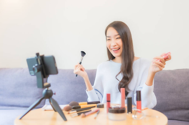Portret piękna młoda azjatycka kobieta przegląd kosmetyki makijaż online w domu - Zdjęcie, obraz