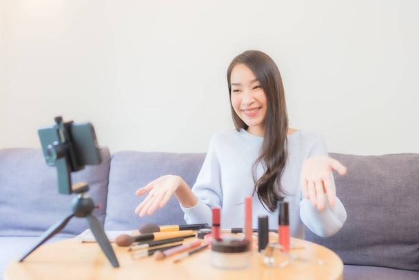 Portrait beautiful young asian woman review cosmetic make up online at home - Foto, afbeelding