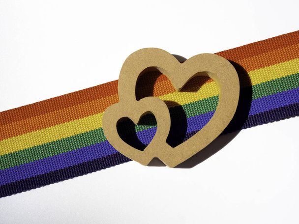 Wooden couple heart on rainbow stripe ribbon isolated on white background. LGBT concept with pride colors and rainbow flag strip. LGBT banner background. - Photo, Image