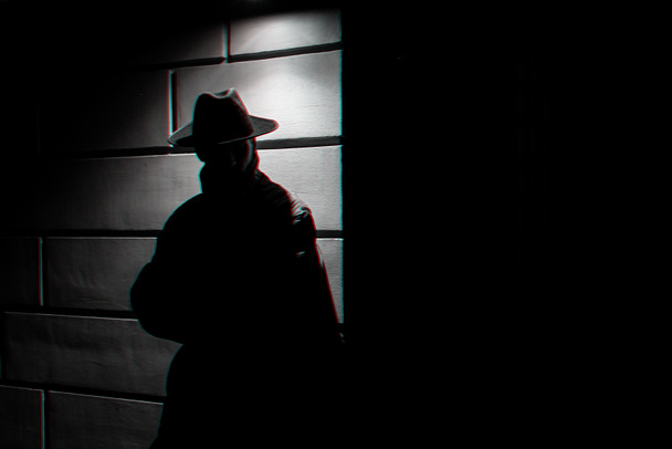 tmavá silueta muže v plášti do deště s kloboukem v noci - Fotografie, Obrázek