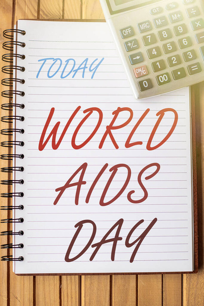 Text caption presenting World Aids Day. Business concept an international day to raised awareness of the AIDS pandemic Blank Open Spiral Notebook With A Calculator Placed On Table. - Valokuva, kuva