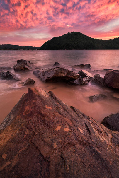 stunning bright pink sunrise at the beach from the rocks - Photo, Image