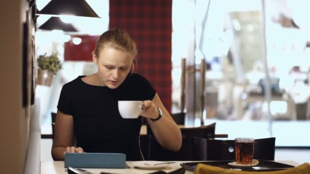 Mujer en la cafetería con almohadilla y beber café
 - Metraje, vídeo