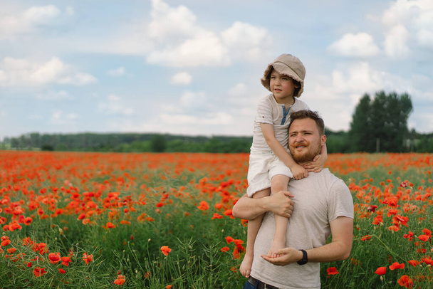 Happy fathers day. Little boy and father are playing in a beautiful field of red poppies. - Photo, Image