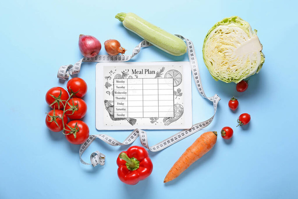 Healthy vegetables, measuring tape and tablet computer with diet plan on screen against color background - Photo, Image