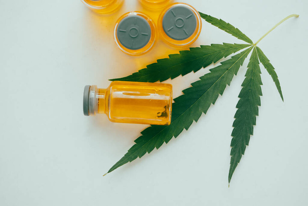 Olio di cannabis nelle fiale con una foglia verde su fondo bianco. Concetto di medicina alternativa. - Foto, immagini