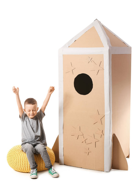 Cute little boy playing with cardboard rocket on white background - Photo, Image