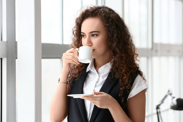 Piękna młoda kobieta pije kawę w biurze - Zdjęcie, obraz
