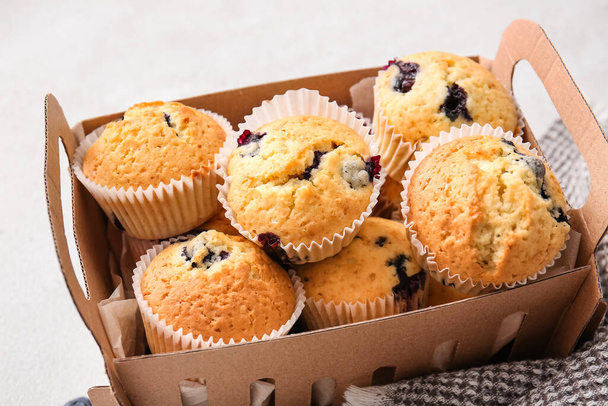 Boîte avec de savoureux muffins aux myrtilles sur fond clair - Photo, image