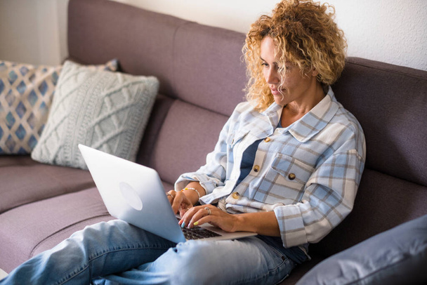Adulto bastante mujeres ver contenido de la computadora de Internet tumbarse y relajarse en el sofá en casa - Foto, Imagen