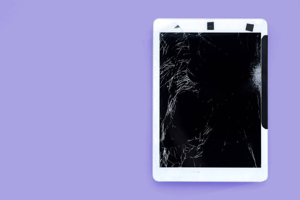 pęknięty lub połamany ekran smartfona lub tabletu tymczasowo przymocowany czarną taśmą na fioletowym pastelowym tle, odizolowany obiekt ze ścieżką wycinania - Zdjęcie, obraz