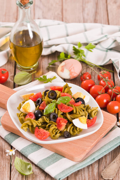 Fusilli pasta with cherry tomatoes, eggs and black olives. - Foto, Bild