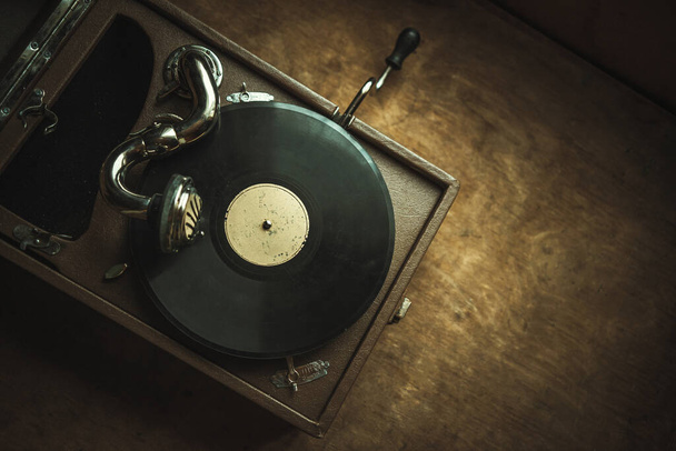 An old wind-up vinyl record player with a handle on a vintage wooden background - Photo, Image