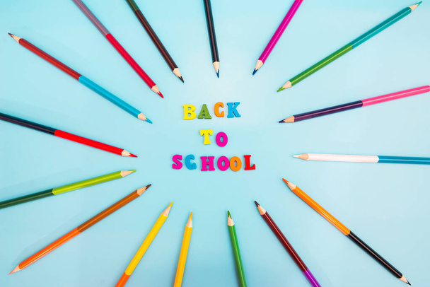 Volver a la escuela de letras de colores y lápices multicolores sobre un fondo azul. - Foto, Imagen