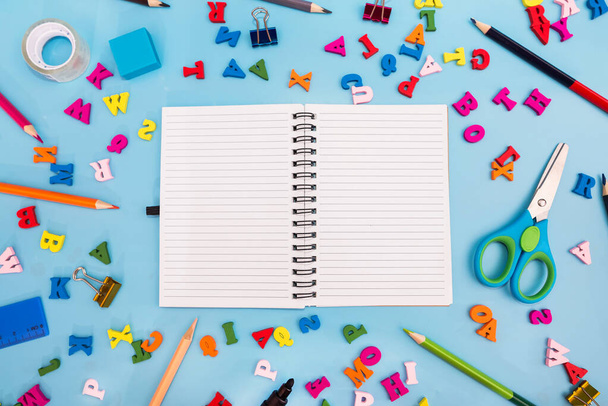 cuaderno blanco en blanco y varios útiles escolares sobre un fondo azul. Concepto escolar. Regreso a la escuela. - Foto, Imagen