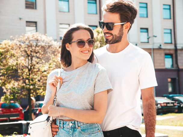 Smiling beautiful woman and her handsome boyfriend. Woman in casual summer clothes. Happy cheerful family. Female having fun. Couple posing on the street background in sunglasses.Hugging each other - Foto, imagen