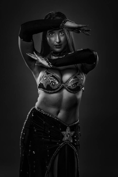Monochrome of an Arab woman belly dancer in red sparkling costume on gray background - Foto, afbeelding
