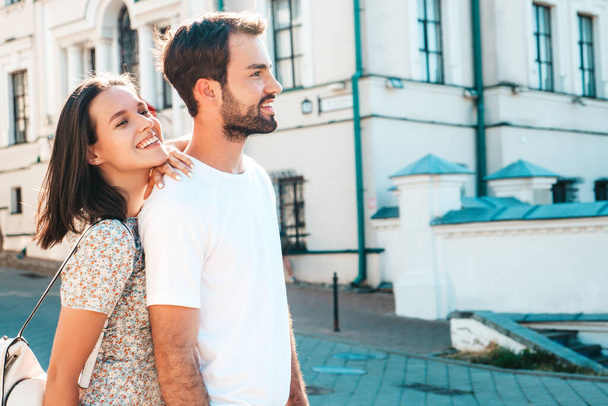 Smiling beautiful woman and her handsome boyfriend. Woman in casual summer clothes. Happy cheerful family. Female having fun. Couple posing on the street background in sunglasses.Hugging each other - Фото, изображение