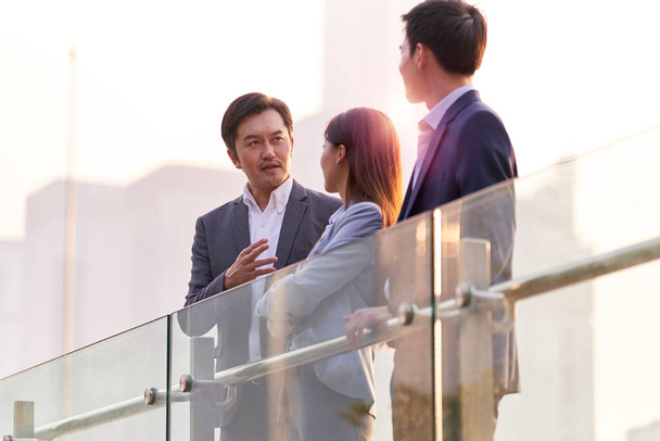 tres feliz asiático empresarios charlando hablando de negocios al aire libre - Foto, Imagen