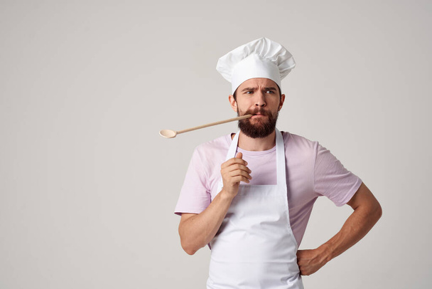 parrakas miespuolinen kokki univormussa lusikka hampaissa työskentelee ravintolassa. Laadukas kuva - Valokuva, kuva