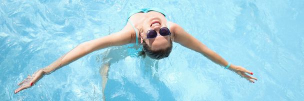 Young woman in sunglasses swimming in pool top view - Fotografie, Obrázek