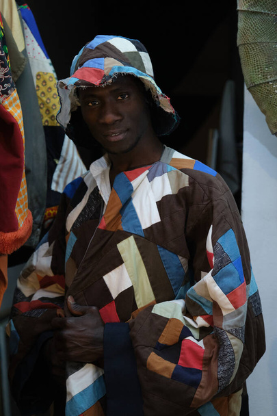 Black man wearing an african item of clothing and looking at camera. African tailor in his sewing workshop. - Photo, Image