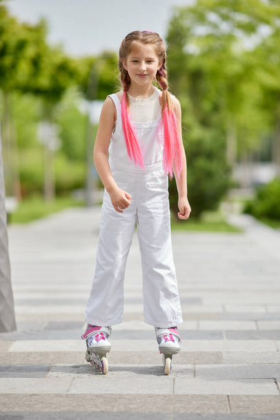 Cheerful little girl on roller skates with braided hair style - Foto, Bild