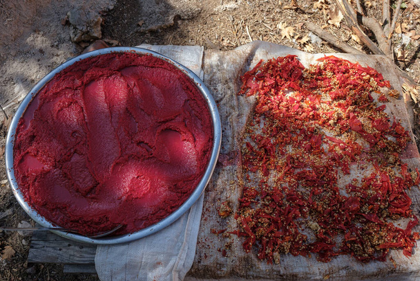 Pimientos rojos picados y pasta de pimienta colocados en el suelo para secar. - Foto, Imagen