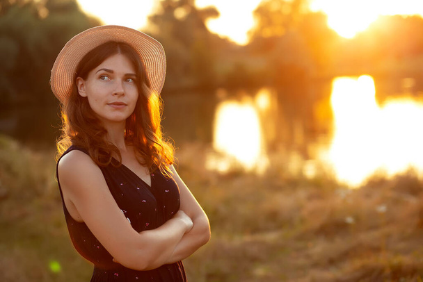 日没の自然の中で藁帽子でリラックスした若い女性のヴィンテージ写真。陽気,自由,幸福,リラックス,化粧の概念 - 写真・画像