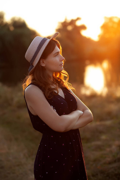 Foto vintage di rilassante giovane donna in cappello di paglia in natura al tramonto. Cheerhul, libertà, felicità, relax, nessun concetto di trucco - Foto, immagini