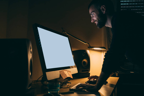 Fiatal szabadúszó férfi dolgozik otthonról éjszaka használ számítógép üres képernyő mosoly  - Fotó, kép