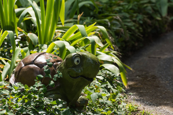 smiling turtle between green plants in a mini golf course from a amusement park on vacation - Photo, Image