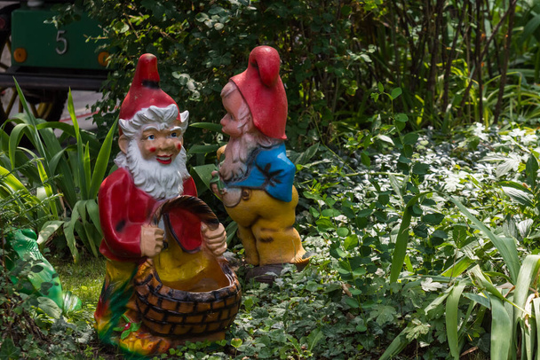 two dwarfs between plants in a mini golf course from a amusement park on vacation - Photo, Image