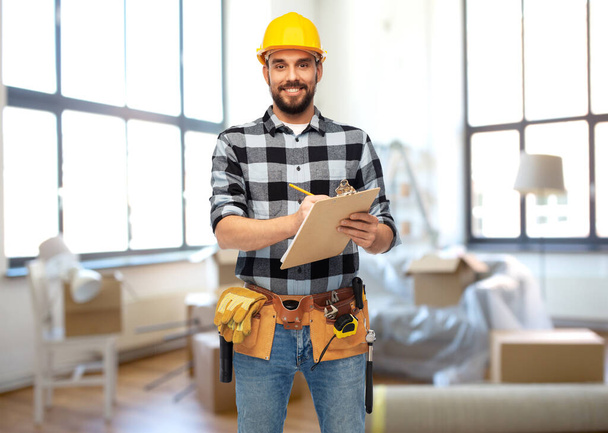 male builder in helmet with clipboard at home - Foto, imagen