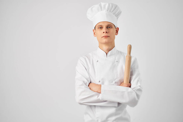 Ένας άντρας με στολή σεφ που κρατάει έναν πλάστη μαγειρεύοντας φαγητό στην κουζίνα. - Φωτογραφία, εικόνα