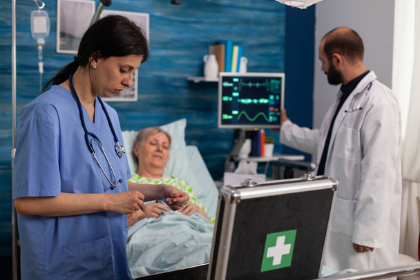 Infirmière spécialiste regardant sac de trousse de médecine tandis que l'homme de soutien social infirmière - Photo, image