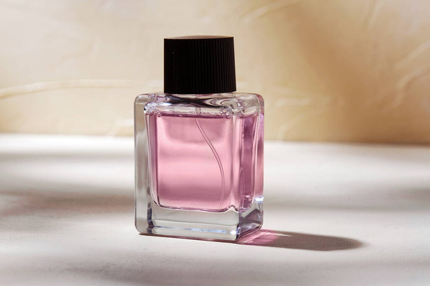 bottle of perfume on white surface with shadows - Foto, afbeelding