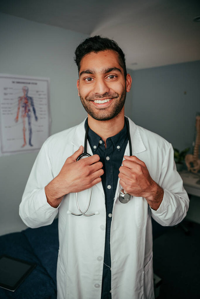 Mezcla de raza sonriente médico masculino de pie en la clínica - Foto, Imagen