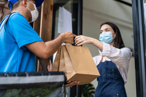 Asian Woman customer wear mask due to Covid-19, order drink to waitress on coffee bar counter. Young girl use sanitizer gel to clean and wash hand before receive takeaway food from restaurant worker - Photo, Image