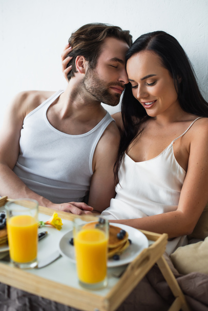 幸せな女性抱擁ひげを生やしたボーイフレンドと朝食トレイを見て  - 写真・画像