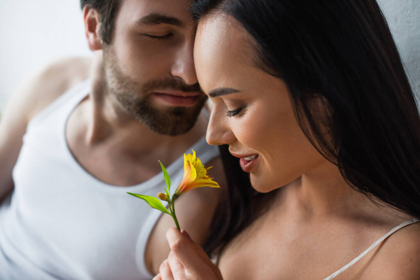happy woman smiling and holding blooming flower near boyfriend  - Photo, Image