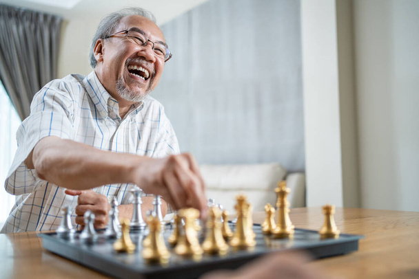 Portret Azjatyckiego Starszego Starszego mężczyzny spędza czas wolny, zostaje w domu po przejściu na emeryturę. Szczęśliwy uśmiech Starszy mężczyzna dojrzały cieszyć się aktywnością w domu gry w szachy. Szpital Opieka zdrowotna i koncepcja medyczna - Zdjęcie, obraz