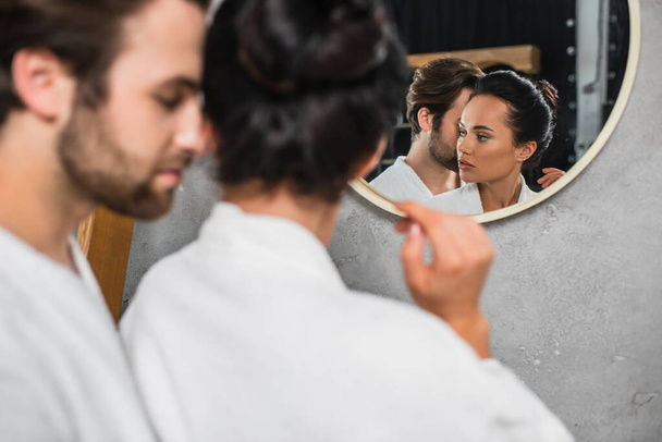 reflection in mirror of young couple in white bathrobes  - Fotoğraf, Görsel