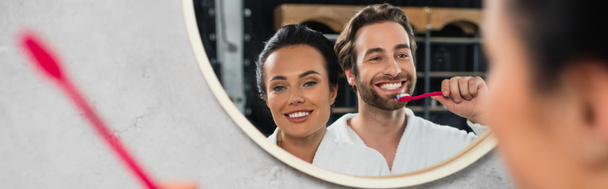 reflection in mirror of happy young couple in white bathrobes brushing teeth, banner - Fotografie, Obrázek