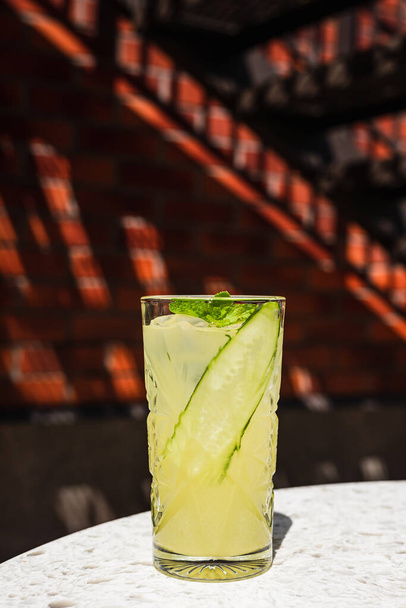A refreshing ginger and pineapple lemonade in a highball glass garnished with a cucumber ribbon and mint - Photo, image