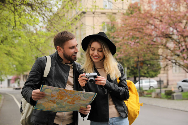 Couple of tourists with map and camera on city street - Foto, imagen
