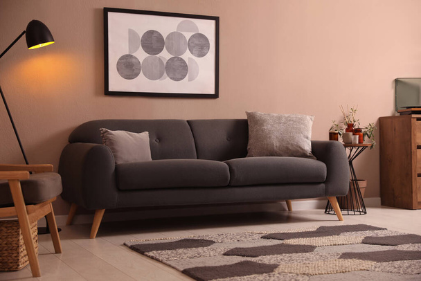 Stylish living room interior with comfortable dark sofa - Φωτογραφία, εικόνα