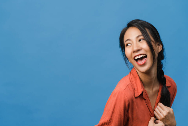 Portret van jonge Aziatische dame met positieve uitdrukking, brede glimlach, gekleed in casual kleding over blauwe achtergrond. Gelukkige schattige blije vrouw verheugt zich succes. Gezichtsuitdrukking. - Foto, afbeelding