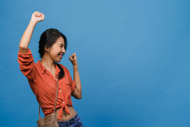 Young Asia lady with positive expression, joyful and exciting, dressed in casual cloth over blue background with empty space. Happy adorable glad woman rejoices success. Facial expression concept. - Foto, imagen